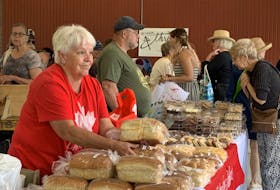 A vendor at the Shelburne Guild Hall Market in Shelburne’s waterfront historic district passes a loaf of homemade bread to a customer. KATHY JOHNSON