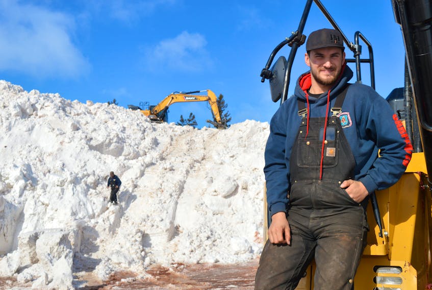BEFORE: On Feb. 8, MacKenzie Stead, an excavator operator with Landmark Construction, stands on his machine with a 13-storey-high pile behind him. Excavators were used to create more room for snow at Charlottetown’s new snow dump site following 185 centimetres of snow that had fallen between Jan. 2 and Feb. 4. File