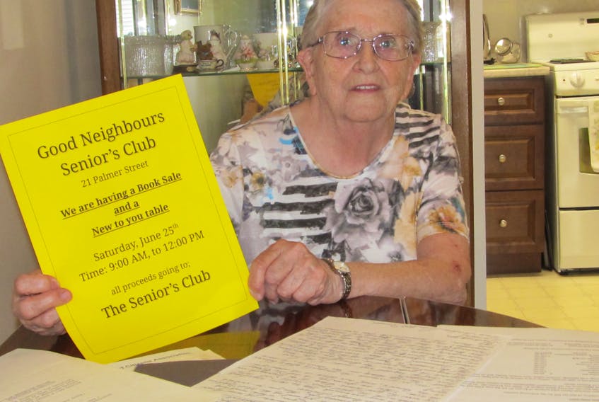 Vie Lynds, the president of the Good Neighbours club, displays a poster for an upcoming fundraiser.