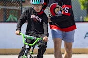  Ottawa Senators defenseman Nick Holden helps 9 year old Abdil Bari learn to ride a bike after bike helmets were given to neighbourhood kids.
