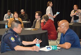Cape Breton Regional Police Const. Jian Ming Hu, left, speaks with Trevor Adams about recruitment opportunities with the police force during an information session at Centre 200 Thursday night. IAN NATHANSON/CAPE BRETON POST