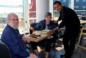 Jim Bowne, left, and his wife, Carolyn, of Baddeck enjoy lunch at Flavor on the Water on Tuesday while engaging with manager Mahesh Prabhu. Prabhu, along with staff, are all maskless. IAN NATHANSON/CAPE BRETON POST