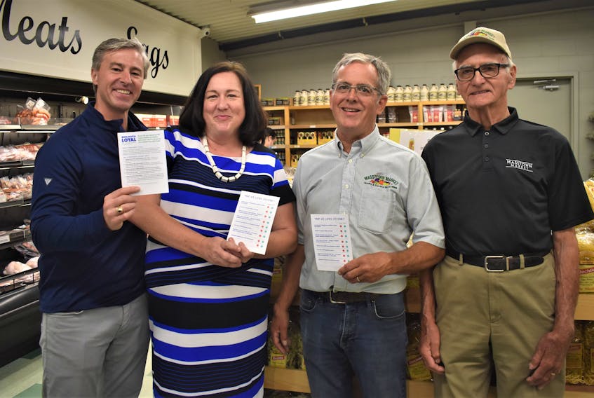 Nova Scotia Premier Tim Houston, Minister of Economic Development Susan Corkum-Greek, Masstown Market owner Laurie Jennings and his father Eric, who founded the business in 1969, display NS Loyal Passport cards which are part of the prototyping phase for the Nova Scotia Loyal program.