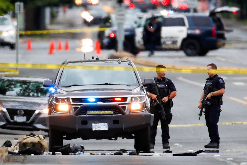 Police officers gather after two armed men entering a bank were killed in a shootout with the police in Saanich, B.C., on Tuesday, June 28, 2022. - Kevin Light / Reuters