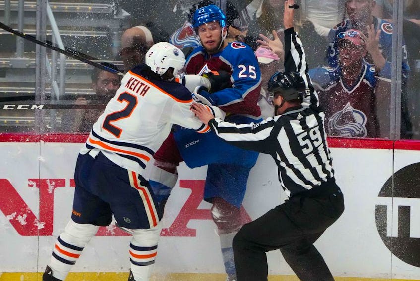Edmonton Oilers defenseman Duncan Keith (2) and Colorado Avalanche right wing Logan O'Connor (25) battle for the puck in front of linesman Steve Barton (59) in the first period of game two of the Western Conference Final of the 2022 Stanley Cup Playoffs at Ball Arena. 