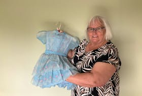 Jackie LeGrow of Bauline holds up the little blue dress she wore 63 years ago when she greeted Queen Elizabeth during a royal visit to Corner Brook on June 20, 1959. - Contributed