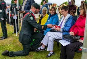 Family members of Pte. John Lambert are presented with the Canadian flag that had dressed the First World War Royal Newfoundland Regiment solder's casket during a funeral service in Belgium Thursday. Canadian Army photo