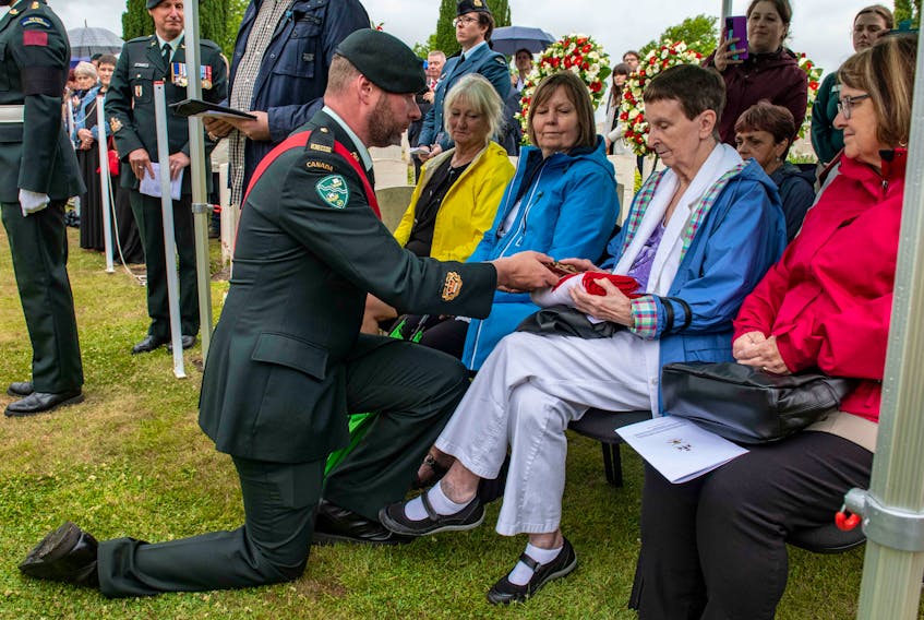 Family members of Pte. John Lambert are presented with the Canadian flag that had dressed the First World War Royal Newfoundland Regiment solder's casket during a funeral service in Belgium Thursday. Canadian Army photo
