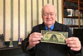 Historian Clyde Macdonald holds a First World War era one-dollar bill along with a dime – the standard pay for a solider of that time period.