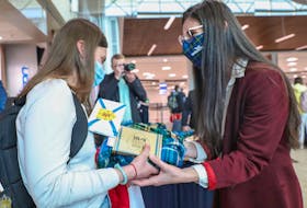 Labour, Skills and Immigration Minister Jill Balser offers a Ukrainian woman gifts, including chocolate from Peace by Chocolate and a My Home Apparel tartan scarf, on behalf of Nova Scotians after a charter flight arrived in Halifax on June. 2. COMMUNICATIONS NOVA SCOTIA PHOTO