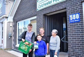 École acadienne de Truro Grade 9 students Gregory Silvocka (left) and Bobby Cameron, as well as Bobby’s little brother Alex, present Colchester Food Bank board chair Vera Faye Smith with $371 and a milk crate of food. The contributions were part of a school assignment for the Grade 9 students, while Alex was happy to help out his big brother and contribute as well.