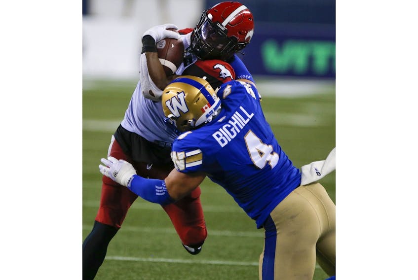  The Blue Bombers’ Adam Bighill tackles Calgary Stampeders running back Ka’Deem Carey during second-half CFL action in Winnipeg on Friday.
