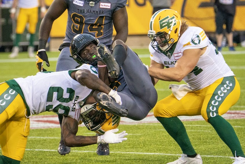 Hamilton Tiger Cats defensive back Lawrence Woods (37) is tackled by Edmonton Elks defensive back Mike Dubuisson (29)and Ante Milanovic-Litre (34) during first half CFL football game action in Hamilton, Ont., on Friday, July 1, 2022.