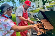 Grace Fenton and Steve Berry were among those barbecuing hotdogs at the Yarmouth South Playground on July 1 as part of the Canada Day festivities and also as part of a tribute to the kindness former Yarmouth teacher John MacNeil showed to his students, especially those from south end, with his hotdog tickets. TINA COMEAU  