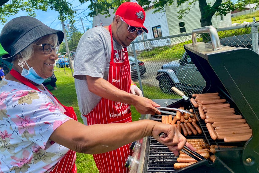 Grace Fenton and Steve Berry were among those barbecuing hotdogs at the Yarmouth South Playground on July 1 as part of the Canada Day festivities and also as part of a tribute to the kindness former Yarmouth teacher John MacNeil showed to his students, especially those from south end, with his hotdog tickets. TINA COMEAU  
