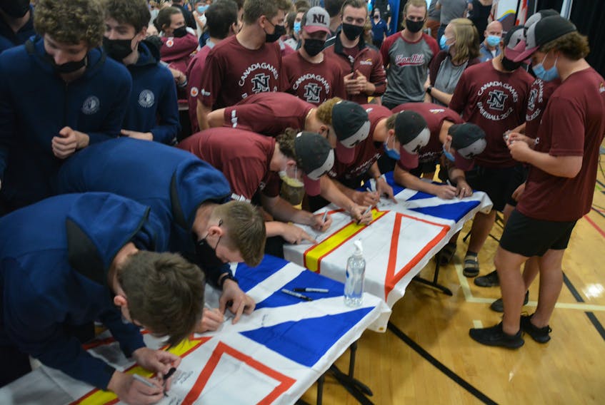 Members of the 2022 Newfoundland and Labrador Canada Games team sign a pair of provincial flags during a rally at the Newfoundland and Labrador Sports Centre on July 19. Nicholas Mercer/The Telegram