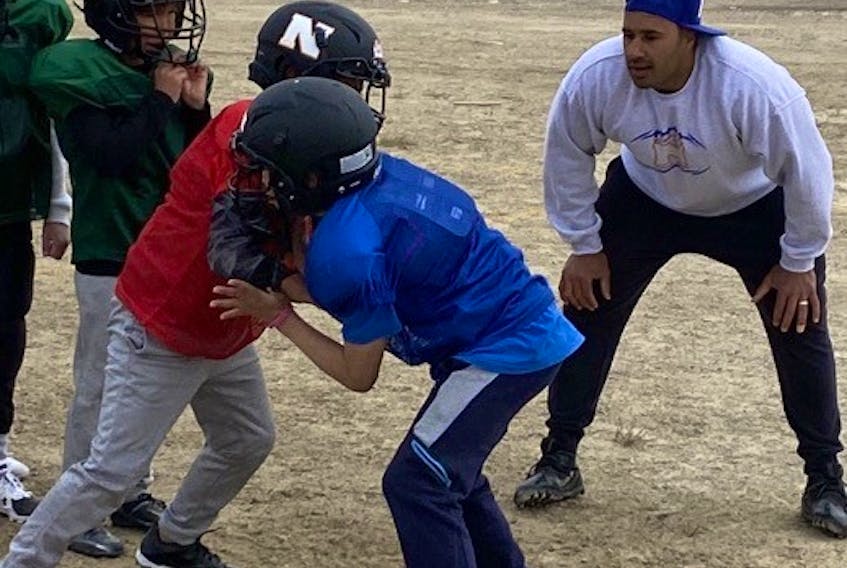 Former Edmonton Elks defensive tackle Eddie Steele works with youngsters at a football camp in Cambridge Bay, Nunavut, on Tuesday, July 19, 2022.