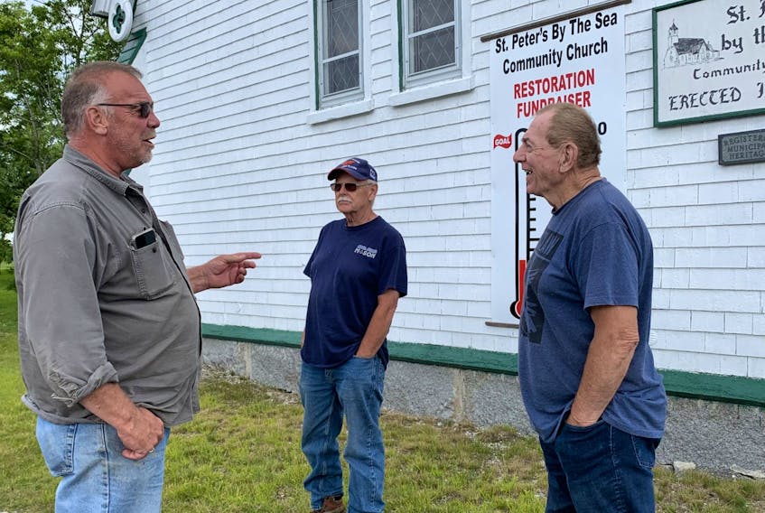 Mike Homes (from left) Richard Stuart and Wayne Butler chat outside the St. Peter’s By the Sea Community Church in Sandy Point while preparing for a free barbecue as a way to thank the community for support of the historic building. KATHY JOHNSON