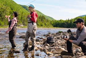 Women’s Fly Weekend participant Afton Jette, left, tries casting a line under the watchful eye of fishing guide Gioia Usher while cameraman Brett Colpitts captures the moment for The New Fly Fisher, a popular television show featured on the World Fishing Network. The show was recently in Cape Breton to film an episode on summer fly fishing on the Margaree River. COMMUNICATIONS NOVA SCOTIA