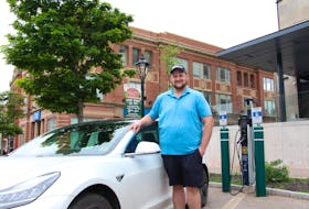 Sam Ferguson stand in front of his new Tesla near an electric charging station in Charlottetown. Rafe Wright • The Guardian