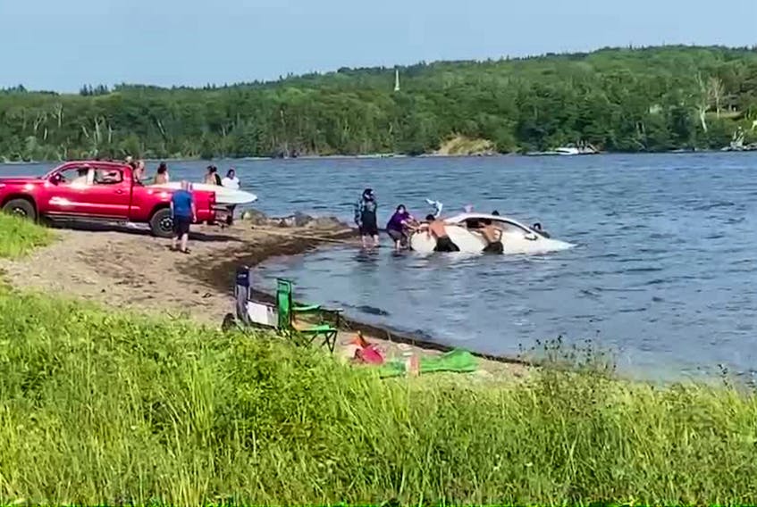 A video still showing about a half-dozen international students helped rescue a sinking vehicle on Sunday at East Bay sand bar. CONTRIBUTED/ISOBEL ARSENEAU