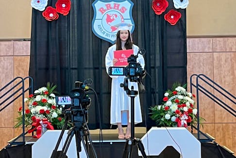 Yumeng (Violet) Li stops for a photo, holding her diploma from Riverview High School in Coxheath, while crossing the stage during her appointed graduation time on June 28. CONTRIBUTED