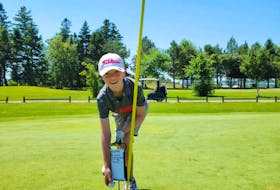 Ten-year-old Archer MacDougall holds the ball just above the cup after sinking a hole-in-one on the No. 6 hole at the Stanhope Golf and Country Club. Archer is believed to be the youngest member ever to record an ace at the course. Contributed