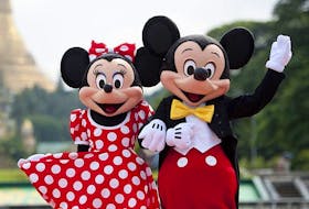 Walt Disney characters Mickey Mouse (R) and Minnie Mouse pose for photographs in front of the Shwedagon Pagoda in Yangon on September 25, 2014.