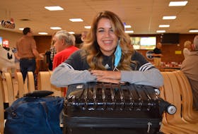 Mattea Stone of Springdale, N.L., sits with her carry-on case at the Charlottetown Airport on July 5. Her advice to anyone who wants to fly anywhere this summer is to pack light. Dave Stewart • The Guardian