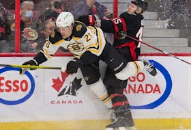 Boston Bruins defenceman Brandon Carlo is taken into the boards by the Ottawa Senators' Parker Kelly in a February 2022 game. The Senators will play their home opener against Boston on Oct. 18.