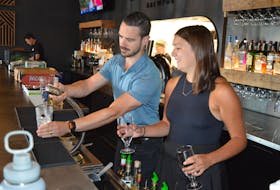 Jared Murphy, left, co-owner of Lone Oak Brewpub in Charlottetown, pours a drink for Emma MacKinnon, a staff member at the pub, on Aug. 1. Dave Stewart • The Guardian