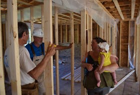 Ed Kennedy, left, and Dave Graham discuss building choices with new homeowner Kaitlyn Williams and her nine-month-old daughter Lila. Ray Burns – The News