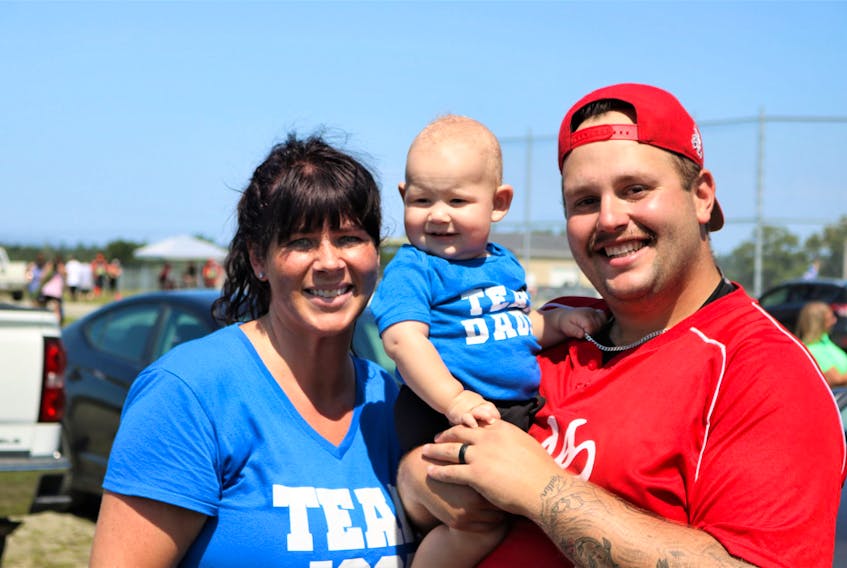 Josh Atkins’ fiancée Krista Hanhams and their youngest son Liam pose for a photo with family friend Brandon Trask during a fundraising softball tournament held Aug. 6 and 7 in Yarmouth County. Hanhams wore a ‘Team Josh’ t-shirt and their two children wore ‘Team Daddy’ shirts as money was raised to assist Josh and his family as he recovers in hospital from a brain injury. JASON ANNIS PHOTO