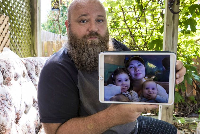 Mathieu Taillefer displays a photo of his wife, Gulmira, and their children Chanel and Tristan. 