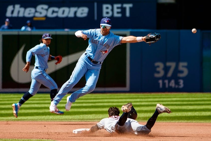 Whit Merrifield of the Blue Jays misses the catch as Tyler Freeman of the Cleveland Guardians steals second base in the fourth inning at Rogers Centre on Sunday, Aug. 14, 2022. 