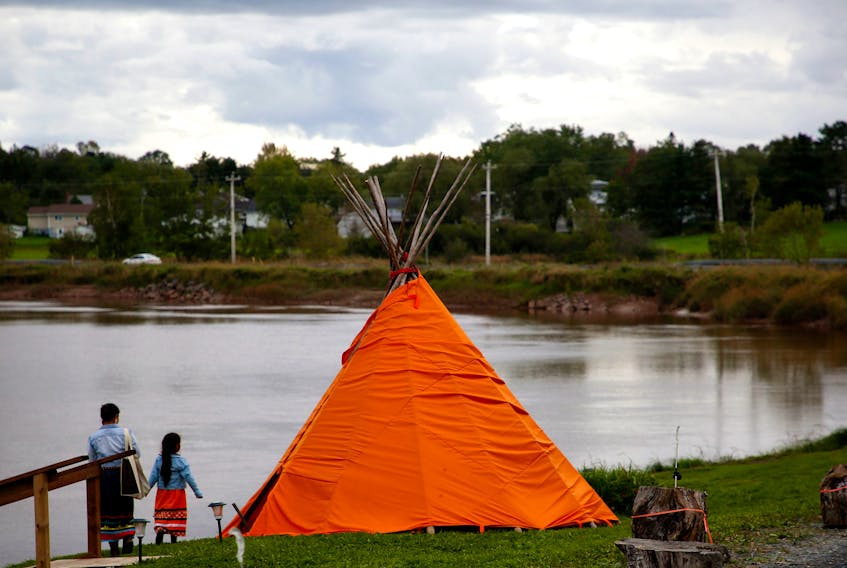 A woman and her daughter walk past a tipi set up on Indian School Road, near the site of the former Shubenacadie residential school, following a plaque unveiling ceremony held on the former grounds in Shubenacadie, N.S. in September 2021. 
