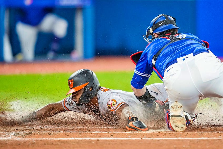 Jorge Mateo of the Baltimore Orioles slides under the tag of Danny Jansen of the Toronto Blue Jays at Rogers Centre on August 15, 2022 in Toronto. 