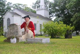Brian McConnell, chair of the Old Holy Trinity Charitable Trust, kneels beside the headstone for Mary Teed Gillis and Donald Archibald Gillis. Mary was instrumental in saving the Old Holy Trinity Church in Middleton.- Jason Malloy