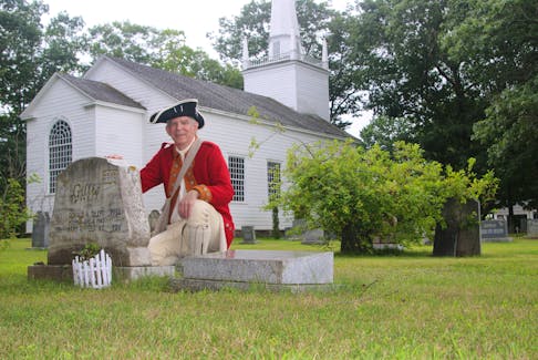Brian McConnell, chair of the Old Holy Trinity Charitable Trust, kneels beside the headstone for Mary Teed Gillis and Donald Archibald Gillis. Mary was instrumental in saving the Old Holy Trinity Church in Middleton.- Jason Malloy