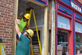 Sarah-Jane Bell, left, and Bradley Gordon with APM MacLean Construction Ltd. make repairs to the main entrance at Water Street Fish and Chips in Charlottetown on Aug. 22 after a Jeep struck the building on Aug. 21. Dave Stewart • The Guardian