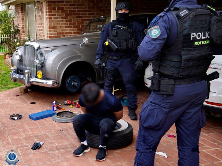  Police photographs of the raid shows the distinctive lines of a metallic silver Bentley in the driveway of a home, under an open car port.