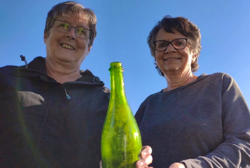 Mona McClintick, left, and Shirley Gallant with bottle they found that contained messages which originated in Florida in 1989. - Contributed