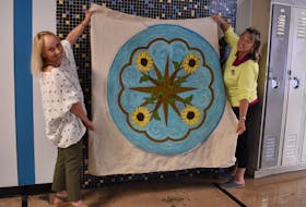 Dianne Griffin, left, and Charlene Miller hold up the rug Miller helped hook for Griffin's mother-in-law, Florence, in Charlottetown July 20. - Alison Jenkins • The Guardian