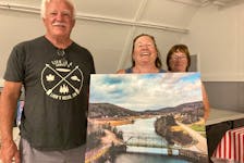 Dave Mansfield, Samantha Dort and Theresa Beiswanger prepare the Country Harbour Gun Club for family movie night. They are holding picture of the 'Iron Bridge' that joins the two sides of the community.