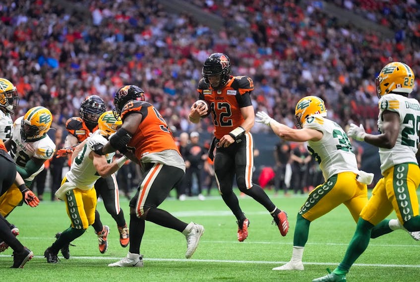 B.C. Lions quarterback Nathan Rourke (12) runs the ball for a touchdown past Edmonton Elks linebacker Adam Konar in Vancouver on June 11, 2022.
