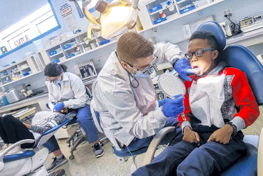 Ari Oba, shows off his teeth to dentistry hygenist student Boyd Roul at the Dal dentristy clinic at Harbourview Elementary in Dartmouth, in 2018.