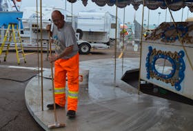 Chucky Kelly with Campbell Amusements brushes rain water off the merry-go-round on Aug. 9. Set up continues for Old Home Week in Charlottetown until the gates open to the public on Aug. 12. Dave Stewart • The Guardian