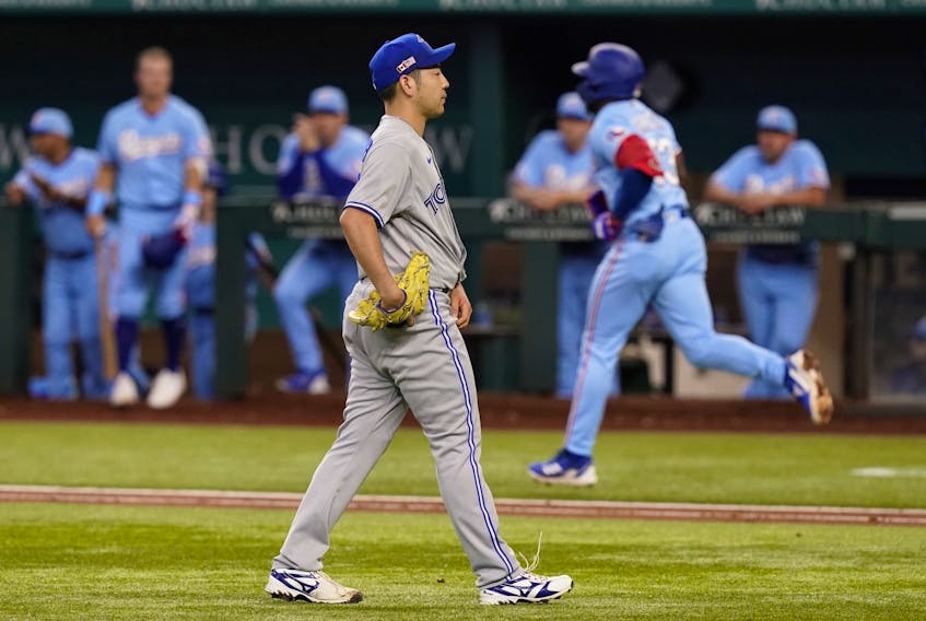 Blue Jays pitcher Yusei Kikuchi, foreground, walks on the field as Texas Rangers' Adolis Garcia, back right, runs the bases after hitting a two-run home run during the third inning in Arlington, Texas, on Sunday, Sept. 11, 2022. 