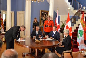 Finance Minister Mark McLane, left, signs the Royal proclamation during the accession proclamation ceremony in Charlottetown, Sept. 12. Also present are, seated from left, Premier Dennis King, Dan Campbell, clerk of executive council, and Lt.-Gov. Antoinette Perry. Standing are Debbie Atkinson, chief of protocol, and RCMP Sgt. Shaun Coady. Alison Jenkins • The Guardian