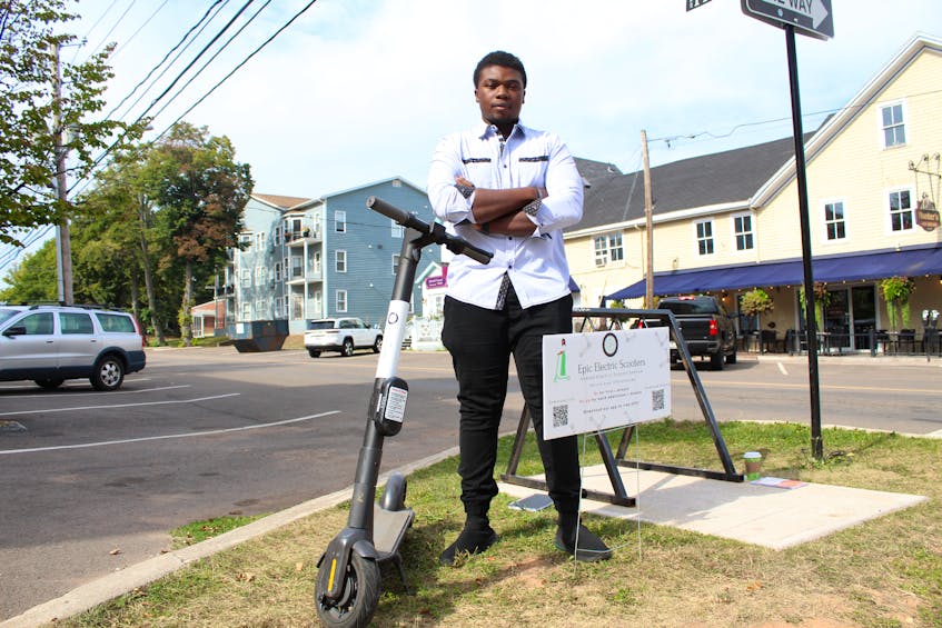 Tafadzwa Mpaso, owner of Epic Electrical Scooters, stands with one of his e-scooters on the corner of Kent Street and Prince Street in Charlottetown on Sept. 12. Rafe Wright • The Guardian